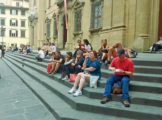  ??  ?? In alto i turisti con i panini acquistati in via de’ Neri seduti sui gradini di piazza San Firenze A sinistra altri turisti in via della Ninna