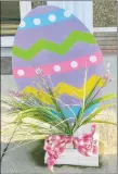  ?? Westside Eagle Observer/SUSAN HOLLAND ?? An egg with lovely pastel design is tied onto one of the front columns at the office of Gravette dentist Dr. Kent Leonard. A small bouquet of spring blossoms, tied with a pretty pink gingham bow, accompanie­s the brightly colored egg.