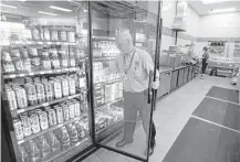  ?? Michael Conroy / Associated Press ?? Jeff Williams checks a beer cooler at Ricker’s convenienc­e store in Sheridan, Ind. The location is one of two where one gas station owner discovered a loophole that allows them to sell cold beer.