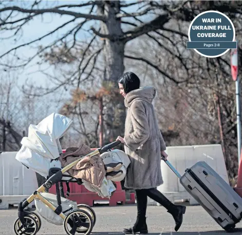  ?? ?? REFUGE: A woman pushes a pram after crossing the border from Ukraine into Siret, Romania.