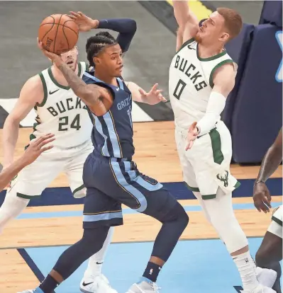  ?? JOE RONDONE/THE COMMERCIAL APPEAL ?? Memphis Grizzlies guard Ja Morant looks to pass the ball as Milwaukee Bucks guard Donte Divincenzo defends during their game at the Fedexforum on March 4, 2021.