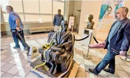  ?? MICKEY WELSH/THE MONTGOMERY ADVERTISER VIA AP ?? Tim Ryals, left, helps sculptor Erik Blome, right, move Blome’s bronze sculpture of Rosa Parks to the front lobby of the Rosa Parks Library and Museum at the Troy University campus in downtown Montgomery, Ala.