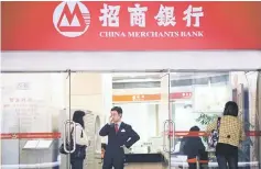  ??  ?? People stand at a branch of China Merchants Bank in Shanghai, China. As regulatory crackdowns in China hit risky investment products and capital outflows, the country’s private banks are looking to profit as they target a bigger share of growing wealth...