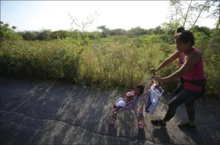  ?? REBECCA BLACKWELL — ASSOCIATED PRESS ?? A woman pushes her daughter in a stroller as a thousands-strong caravan of Central Americans hoping to reach the U.S. border moves onward from Juchitan, Oaxaca state, Mexico, Thursday. Thousands of migrants resumed their slow trek through southern Mexico on Thursday, after attempts to obtain bus transport to Mexico City failed.