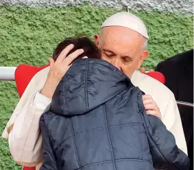  ??  ?? Emozione Il piccolo Emanuele di 8 anni, che da poco ha perso il padre, riceve l’abbraccio di Papa Francesco durante la visita alla parrocchia di San Paolo della Croce a Corviale, alla periferia ovest di Roma