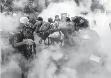  ??  ?? Protesters struggled with tear gas in clashes with riot police during a protest in Caracas