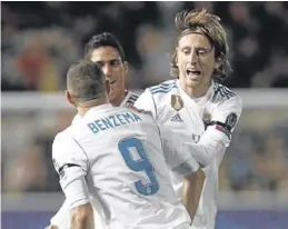  ?? REUTERS / YIANNIS KOURTOGLOU ?? Varane y Modric felicitan a Benzema tras uno de sus goles.