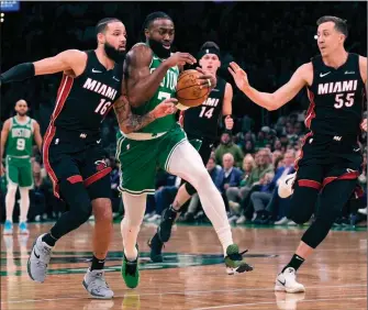  ?? Boston Celtics guard Jaylen Brown, centre, drives to the basket between Miami Heat’s Caleb Martin (16) Duncan Robinson (55) during Game 2 of the NBA first-round playoff series Wednesday in Boston. ?? THE ASSOCIATED PRESS