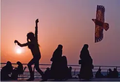  ??  ?? This file photo shows a girl plays with her kite as visitors walk on the Red Sea beach, in Jiddah, Saudi Arabia.