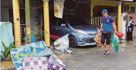 ?? (Foto BERNAMA) ?? Penduduk Taman Aman Kota Tinggi membuang barang yang rosak selepas dilanda banjir.