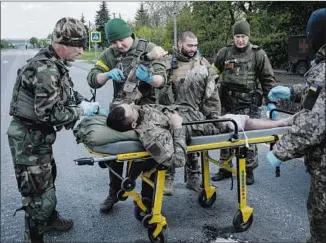  ?? Yasuyoshi Chiba AFP/Getty Images ?? MEMBERS OF a Ukrainian army unit treat a wounded soldier near Lysychansk, Ukraine.