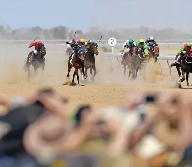  ?? Picture: AFP ?? Horses in the first race thunder past the crowd at the Birdsville Races yesterday. The annual races in Outback Queensland attract thousands to the remote town and is a major source of tourist revenue.