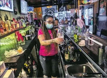  ?? Robert Gauthier Los Angeles Times By John Myers, Alex Wiggleswor­th, Laura Newberry and Gale Holland ?? CHRISTINA FLINTLAND works behind plexiglass at Elvie’s Inn in Covina on Sunday. The bar will close Monday, albeit under protest. “We can’t keep shutting down businesses at a moment’s notice,” its owner said.