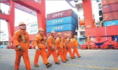  ?? YU FANGPING / FOR CHINA DAILY ?? Workers walk past containers at Qingdao Port, Shandong province.