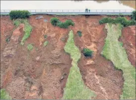  ?? AFP ?? An aerial view shows people inspecting a section of the Steinbach hydrolic dam in Euskirchen, western Germany, which was damaged by flashflood­s.