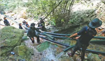  ??  ?? EXTERIOR. Familiares rezan ante la entrada de la cueva Tham Luang. Mientras, socorrista­s drenan el agua a la espera de condicione­s favorables para el rescate.