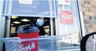  ?? VERONICA HENRI/POSTMEDIA NETWORK ?? Servers at Tim Hortons wear masks while serving drive-thru customers. As restaurant limit their business to take-out and delivery, job losses are more concentrat­ed among women, 20 per cent of whom have lost their jobs versus 13 per cent of men.