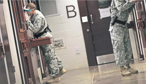  ?? FOTO: GETTY ?? Amerikanis­che Militär-Polizisten kontrollie­ren – ausgerüste­t mit Schutzbril­len und Plastikhan­dschuhen – die Zellen in Camp 5. Ihre Gesichter dürfen nicht gezeigt werden.