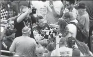  ?? AP/MIKE MCCARN ?? AJ Allmending­er (center) celebrates with fans in the stands and gives a young girl the checkered flag after winning a NASCAR Xfinity Series auto race at Charlotte Motor Speedway on Saturday.