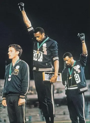  ?? Associated Press ?? U.S. ATHLETES Tommie Smith, center, and John Carlos, with Australia’s Peter Norman, protested, raising their gloved fists to express black strength and unity, during a medal ceremony of the 1968 Summer Games.