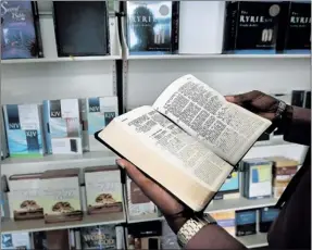  ?? JIM WEBER/ THE COMMERCIAL APPEAL ?? Ferrick Gale shows off some of the Bibles on display at the front of the Church of God in Christ Bookstore Downtown. The church maintains the store as community service.