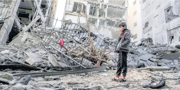  ??  ?? Un niño palestino observa las ruinas de un edificio de departamen­tos que fue destruido tras un ataque aéreo israelí en la ciudad de Gaza.