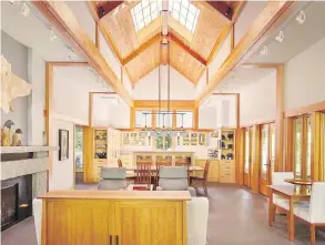  ??  ?? Douglas fir milled from trees on-site covers the cathedral ceiling in the great room, with maple cabinetry throughout the kitchen. Right, a perfect spot for crossword puzzles and upclose nature viewing, the seating area in the great room looks through...