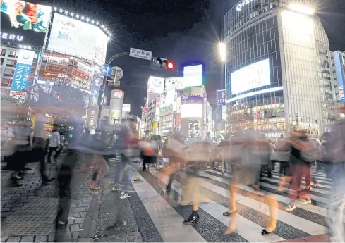  ?? REUTERS ?? Pedestrian­s walk at a scramble crossing at Shibuya district in Tokyo.