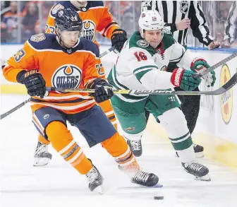  ?? JASON FRANSON, THE CANADIAN PRESS ?? Oilers forward Ryan Spooner and Wild winger Matt Hendricks battle for the puck during first-period action in Edmonton on Friday.