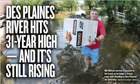  ?? | MARK WELSH/ DAILY HERALD ?? Bill Wilson carries a vacuum to his truck as he helps a friend cope with flooding in Des Plaines on Saturday.