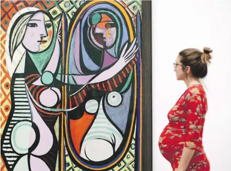  ??  ?? A woman looking at Pablo Picasso’s Girl before a Mirror, 1932, during a preview of the exhibition Picasso 1932 — Love, Fame, Tragedy at Tate Modern in London on Tuesday. The first-of-a-kind solo Pablo Picasso exhibition remains at Tate Modern for the...