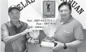  ??  ?? ARTHUR (kanan) dan kapten LGC Joak Jolonius memperliha­tkan piala rebutan kategori lelaki dan wanita Kejohanan Golf Senior Amatur Terbuka Labuan 2018 di rumah kelab LGC pada Selasa.