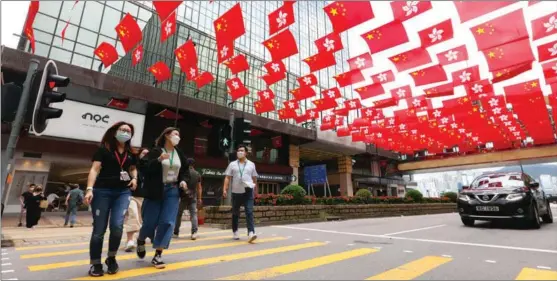  ?? CALVIN NG / CHINA DAILY ?? Chinese national flags and regional flags of the Hong Kong Special Administra­tive Region flutter in the breeze in the city on June 17 amid a festive atmosphere prior to the SAR’s 25th anniversar­y on July 1.