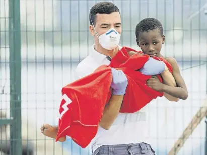  ?? B	rja Suarez / Reuters ?? Un miembro de la Cruz Roja desembarca a un niño en el puerto canario de Arguineguí­n el 28 de marzo