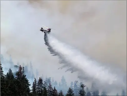  ?? RICK SILVA/PARADISE POST ?? A helicopter drops water on the Dixie Fire on Aug. 14, 2021near Pulga, California the day after the fire started in the Feather River Canyon. PG&E denies that it flew a drone at the time of the fire, temporaril­y suspending air operations on Aug. 13.