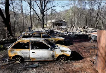  ?? The Associated Press ?? WHAT REMAINS: Charred home and cars sit on a property, while a neighbor’s home, background, is undamaged Thursday in Gatlinburg, Tenn. A devastatin­g wildfire destroyed numerous homes and buildings on Monday.