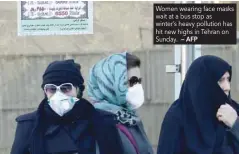  ?? — AFP ?? Women wearing face masks wait at a bus stop as winter’s heavy pollution has hit new highs in Tehran on Sunday.