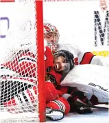  ?? GETTY IMAGES ?? Hawks forward Andreas Athanasiou and Hurricanes goalie Pyotr Kochetkov get tangled up after colliding during the third period.