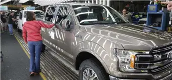  ?? AP FILE ?? FINISHED PRODUCT: Workers give a final look to a Ford F-150 truck on the assembly line at a plant in Dearborn, Mich.