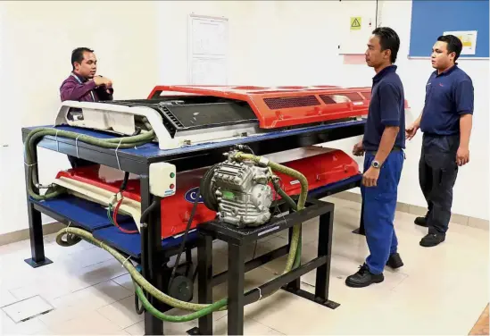  ??  ?? Mechanics at the academy going through the air conditioni­ng system of a bus, which is typically mounted on the roof.