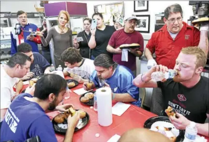  ?? ARNOLD GOLD — NEW HAVEN REGISTER ?? Paul Ciocca, top right, owner of Eddy’s Bake Shop, watches Nick Wehry, bottom right, of Torrington on his way to winning the 19th annual paczki eating contest in Ansonia Tuesday.