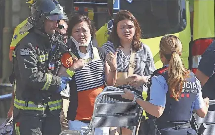  ??  ?? Injured people are treated Thursday in Barcelona, Spain, after a white van jumped the sidewalk in the historic Las Ramblas district, crashing into a crowd of residents and tourists, police said.