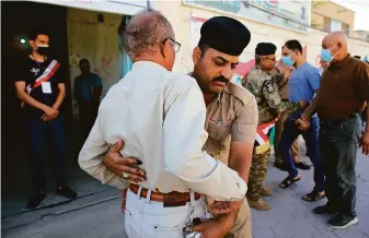  ?? Nabil al-Jurani / Associated Press ?? Iraqi security officers search voters at a polling site in Basra. Negotiatio­ns to choose a prime minister tasked with forming a government are expected to drag on for weeks or even months.