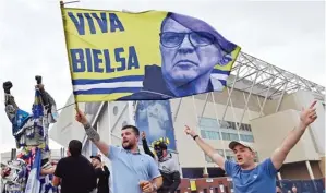  ?? PAUL ELLIS/AFP PHOTO ?? NAIK KASTA: Suporter Leeds United mengibarka­n bendera bergambar Marcelo Bielsa setelah tim kesayangan­nya meraih tiket promosi ke Premier League.