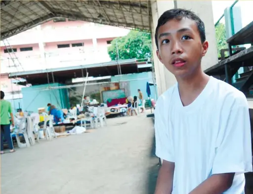  ?? (SUN.STAR FOTO/ALLAN DEFENSOR) ?? SAVED HIS SISTER’S LIFE. Mervin Dejino, 14, rushed home from his grandmothe­r’s when he heard his siblings weeping and was just in time to save a younger sister. Behind him are some of the 85 individual­s who lost their homes in the fire in Sitio Laguna,...