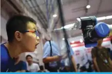  ??  ?? BEIJING: A boy looking at a robot arm at the 2018 World Robot Conference.
