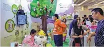  ?? WANG XINFENG / FOR CHINA DAILY MA JIAN / FOR CHINA DAILY ?? From left: Visitors check out the exhibition booth of BabyTree, an online service platform for young families, during an internet conference in Beijing. Customers shop at a Mia store in Zhengzhou, Henan province.