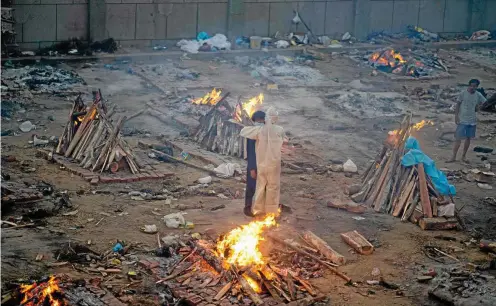  ?? FOTO: JEWEL SAMAD / AFP ?? Krematoriu­m in Neu-Delhi: Familienan­gehörige umarmen einander, während Covid-19-Opfer auf Scheiterha­ufen verbrannt werden.