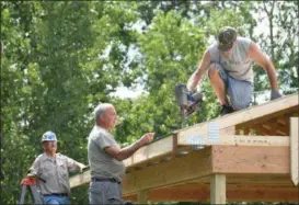  ?? ERIC BONZAR — THE MORNING JOURNAL ?? Vietnam veterans Joe Horvath, left, and John Sekletar, right, work with volunteer John McKiel to cover the roof of the Vietnam Veterans Memorial of Lorain County pavilion, 625 N. Lake St., Amherst, July 26. Through the fundraisin­g efforts of the...