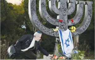  ?? (Valentyn Ogirenko/Reuters) ?? A MAN places a candle at a ceremony near a monument commemorat­ing the victims of Babi Yar.